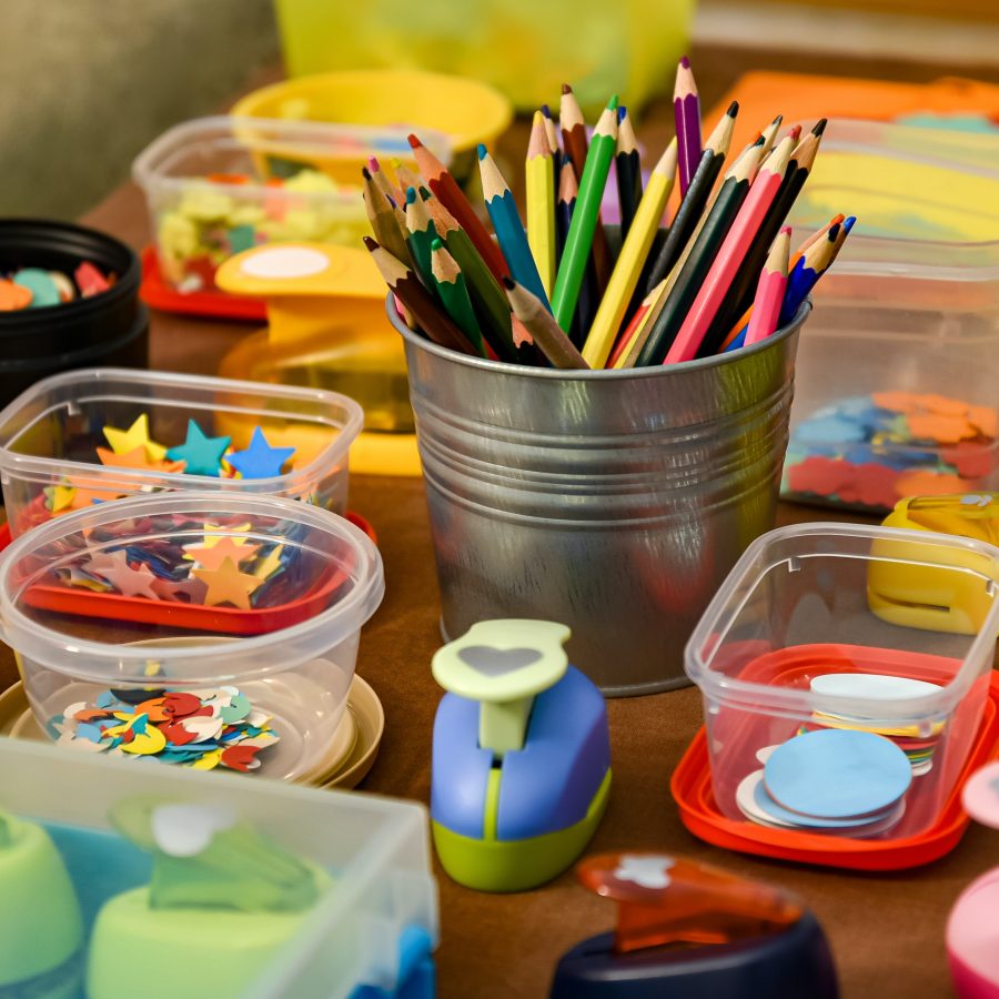 A table of craft materials including pens, pencils and coloured paper.